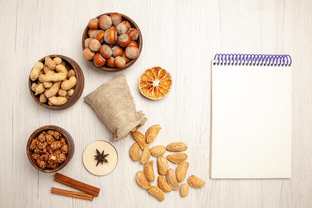 Vue de dessus différentes noix à l'intérieur de petits pots sur un bureau blanc collation noix noix noisette