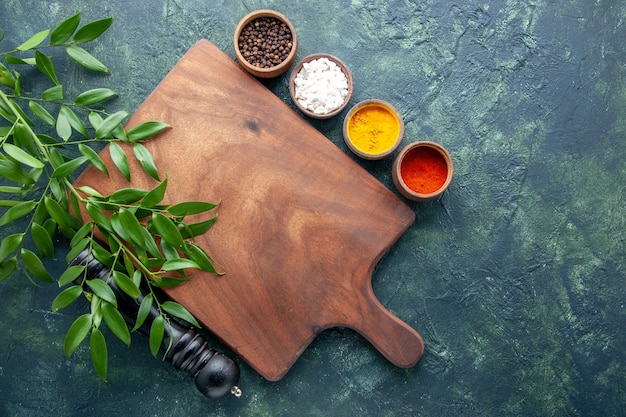 Vue de dessus différents assaisonnements avec bureau en bois marron sur la surface bleu foncé couleur bois coutellerie forte arbre cuisine verte