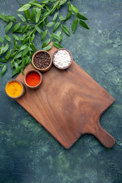 Photo gratuite vue de dessus différents assaisonnements avec bureau en bois marron sur table bleu foncé bois de couleur bois vert cuisine vert