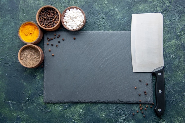 Vue de dessus différents assaisonnements avec grand couteau sur la surface bleu foncé des aliments épices poivre photo couleur sel