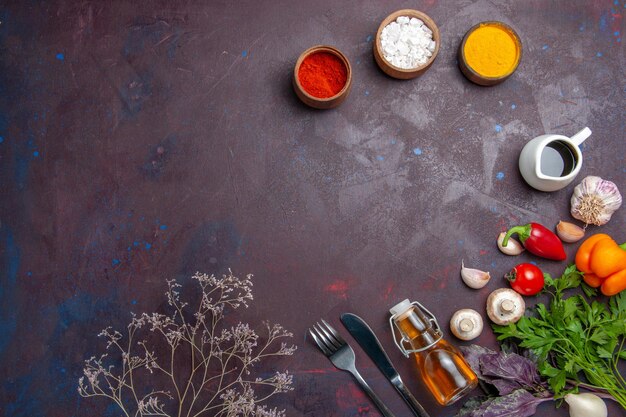 Vue de dessus différents assaisonnements avec des légumes frais sur une surface sombre nourriture épicée salade de poivre santé