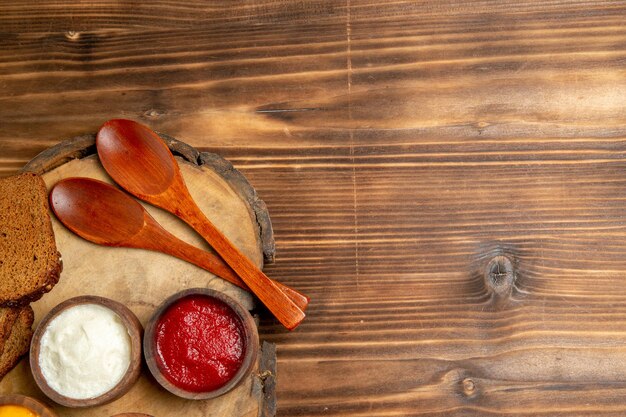 Vue de dessus de différents assaisonnements avec des miches de pain noir sur une table brune