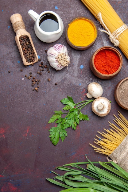 Photo gratuite vue de dessus différents assaisonnements avec des pâtes crues et des champignons sur une surface sombre repas de produits alimentaires crus