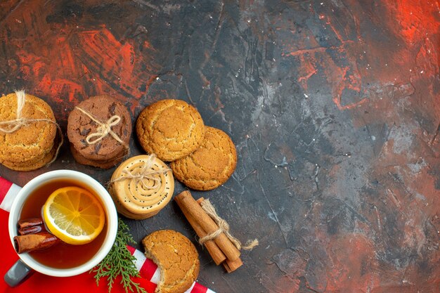 Vue de dessus différents biscuits attachés avec une tasse de corde de thé bâtons de cannelle sur une table rouge foncé avec place libre