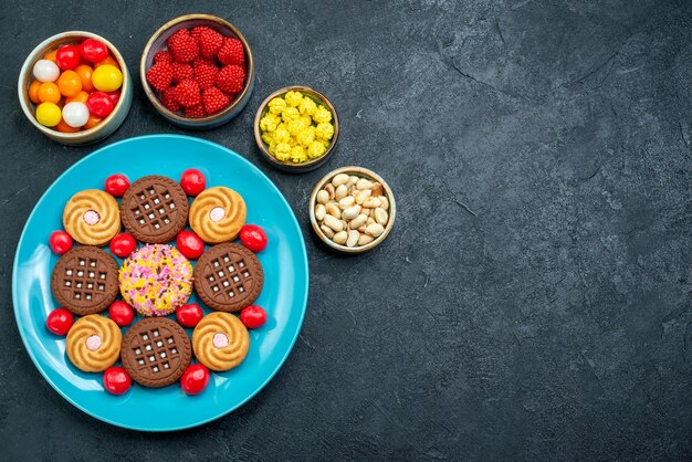 Vue de dessus différents biscuits au sucre avec des bonbons sur la surface grise sucre candy biscuit sucré