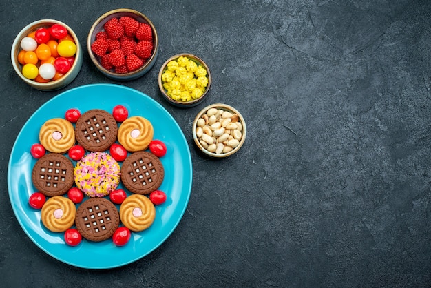 Vue de dessus différents biscuits au sucre avec des bonbons sur la surface grise sucre candy biscuit sucré