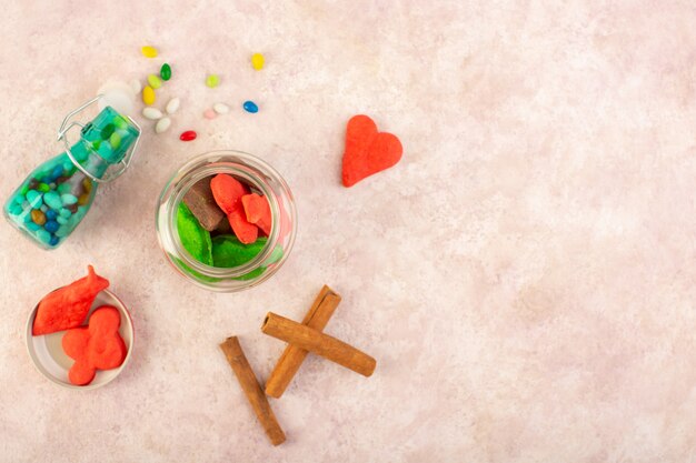 Vue de dessus de différents biscuits sucrés et délicieux avec de la cannelle et des bonbons sur la surface rose