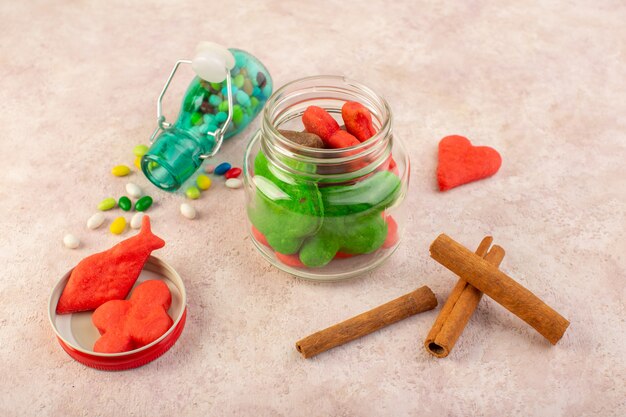 Vue de dessus de différents biscuits sucrés et délicieux avec de la cannelle et des bonbons sur la surface rose