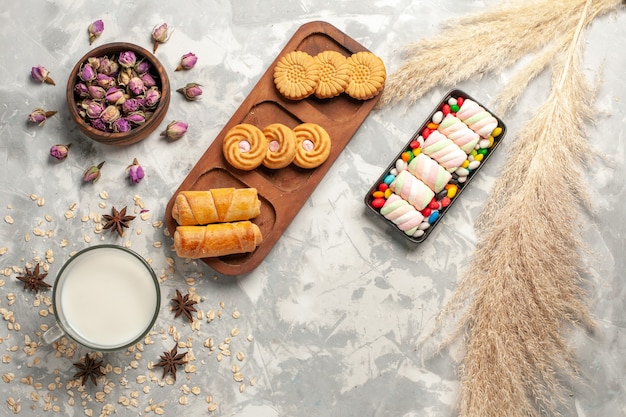 Vue de dessus différents biscuits sucrés avec du lait et des bonbons sur fond blanc sucre candy biscuit sucré tarte gâteau cookie