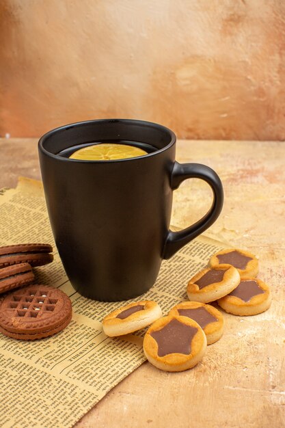 Vue de dessus de différents biscuits et thé dans une tasse noire sur fond de couleur mixte