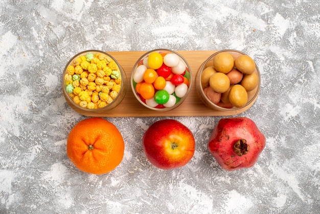 Vue de dessus de différents bonbons sucrés avec des fruits sur une surface blanche