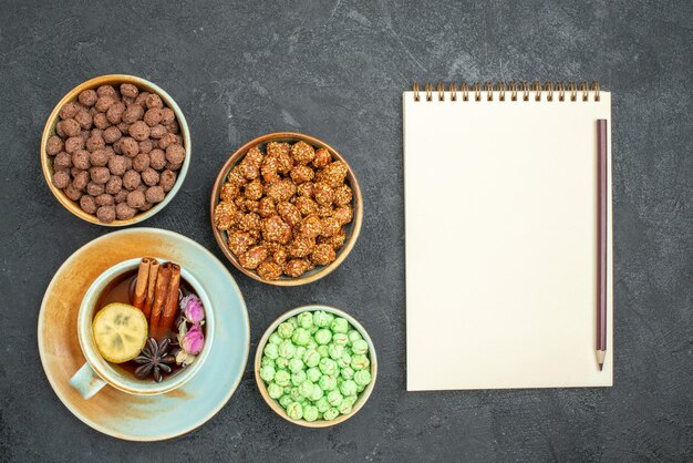 Vue de dessus de différents bonbons sucrés avec une tasse de thé sur fond gris