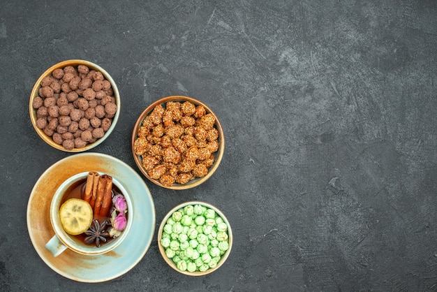 Vue de dessus de différents bonbons sucrés avec une tasse de thé sur fond gris