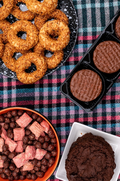 Vue de dessus différents cookies et boules de céréales sur une surface sombre