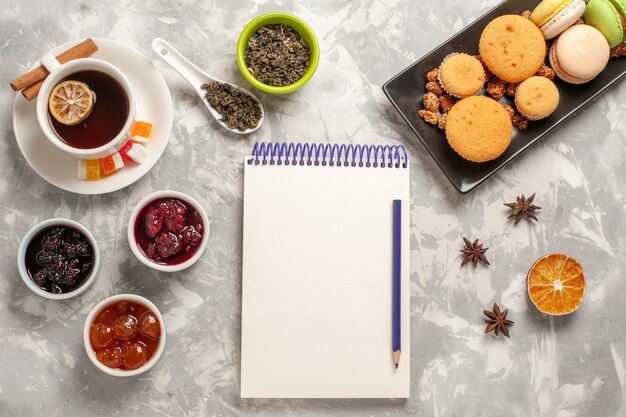 Vue de dessus différents cookies avec différentes confitures et tasse de thé sur fond blanc biscuit gâteau tarte au sucre biscuits sucrés