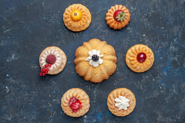 Vue de dessus de différents délicieux gâteaux à la crème et aux baies sur noir, berry fruits cuire gâteau biscuit sucré