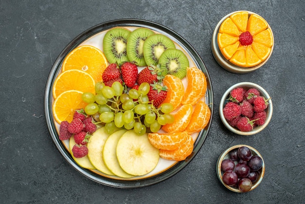 Vue de dessus différents fruits composition fruits frais et tranchés sur fond sombre santé fruits frais mûrs mûrs