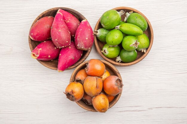 Vue de dessus différents fruits frais à l'intérieur des assiettes sur un bureau blanc fruits tropicaux régime mûr couleur exotique vie saine