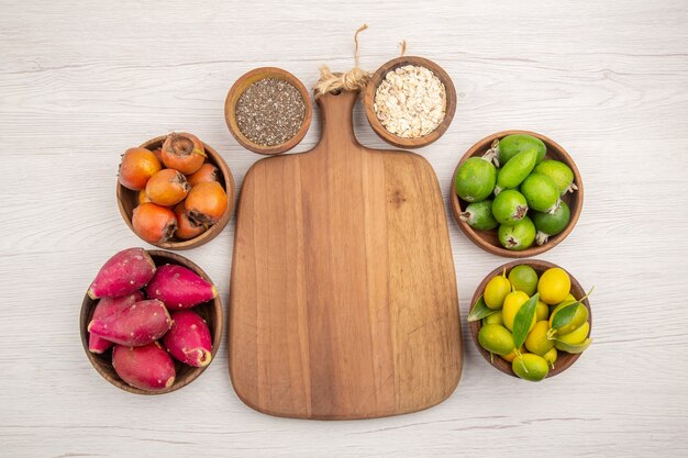 Vue de dessus différents fruits frais à l'intérieur des assiettes sur fond blanc régime de couleur de vie sain exotique mûr tropical