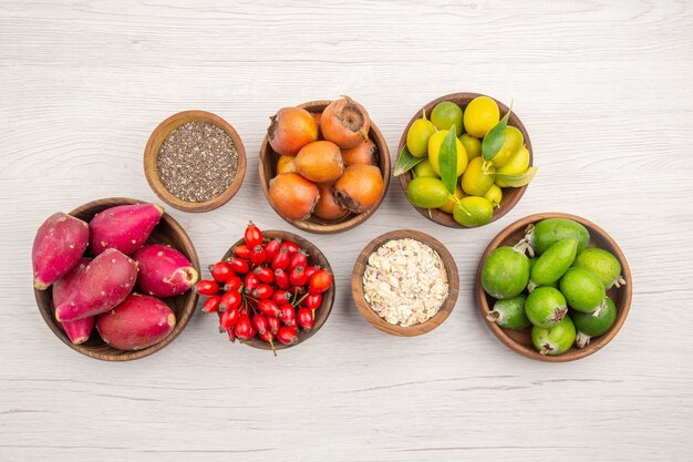 Vue de dessus différents fruits frais à l'intérieur des assiettes sur fond blanc vie saine mûre régime de couleur tropicale