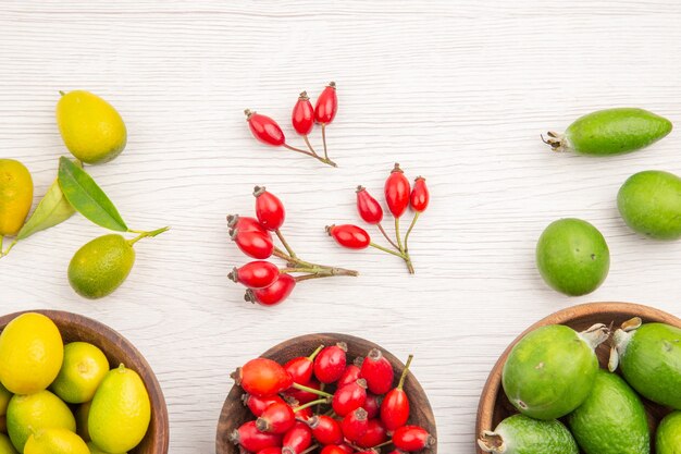 Vue de dessus différents fruits frais à l'intérieur des assiettes sur sol blanc couleur de régime alimentaire mûr exotique vie saine tropicale