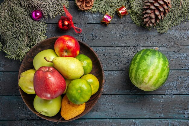 Vue de dessus différents fruits frais à l'intérieur de la plaque sur la composition de couleur de fruits de bureau bleu foncé frais mûrs