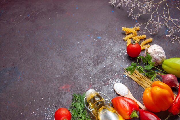 Vue de dessus différents ingrédients pâtes crues et légumes frais sur fond sombre produit alimentaire santé salade régime