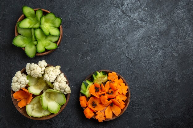 Vue de dessus différents légumes conçus à l'intérieur de pots sur un espace gris foncé
