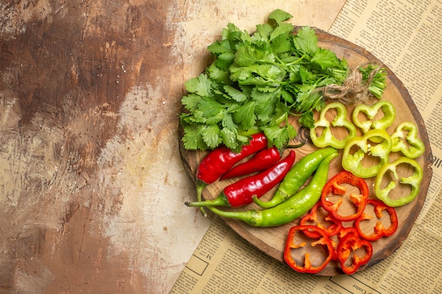 Vue de dessus différents légumes coupés en morceaux sur une planche de bois d'arbre rond sur fond ambre