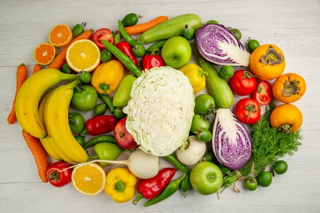 Vue de dessus différents légumes avec des fruits frais sur fond blanc clair salade nourriture santé couleur régime mûr
