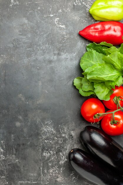 Vue de dessus différents légumes tomates poivrons aubergines sur fond gris