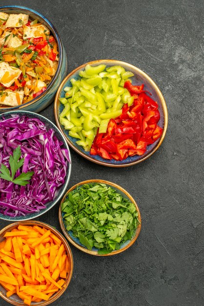 Vue de dessus différents légumes en tranches avec salade de poulet sur le régime de salade santé sol sombre