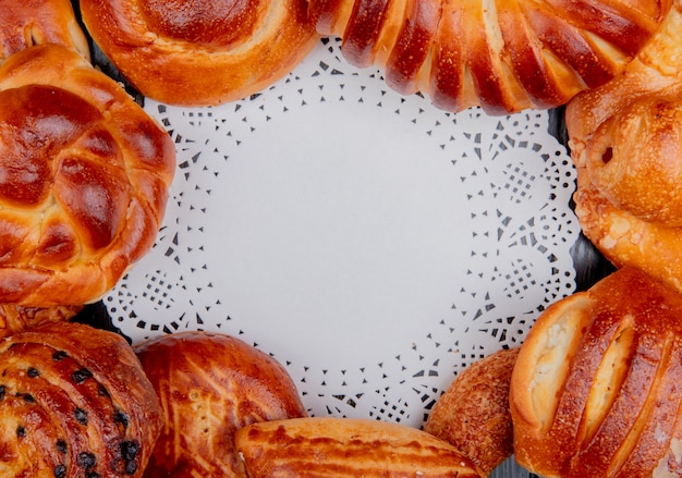 Vue de dessus de différents produits de boulangerie mis en forme ronde autour de papier napperon comme arrière-plan