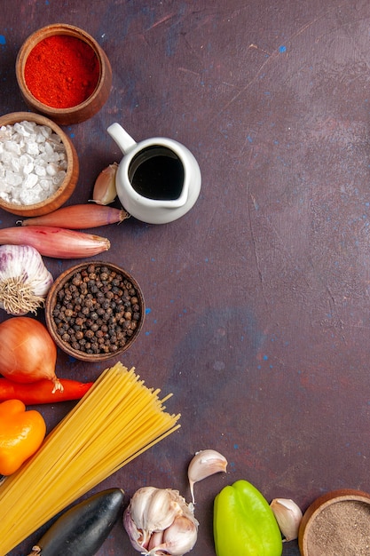 Vue de dessus différents produits avec des légumes et des assaisonnements sur fond sombre repas alimentaire salade de santé des légumes