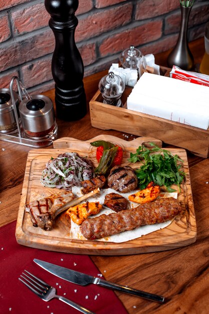 Vue de dessus de différents types de kebab avec oignons et herbes sur une planche de bois