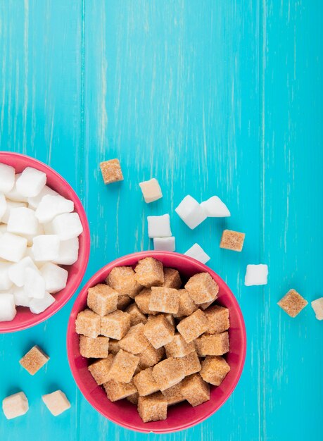 Vue de dessus de différents types de morceaux de sucre dans des bols sur fond de bois bleu