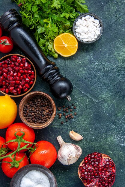 Vue de dessus diverses épices moulin à poivre tomates ail verts grenade sur table