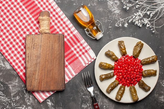 Vue de dessus dolma feuille savoureuse avec des grenades sur fond sombre