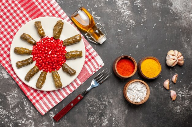 Vue de dessus dolma feuille savoureuse avec des grenades sur un sol sombre