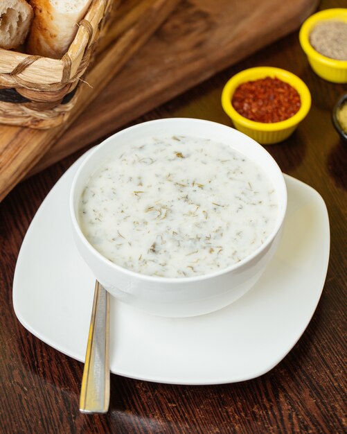 Une vue de dessus dovga avec des verts à l'intérieur de la plaque blanche sur le bureau en bois brun nourriture soupe yaourt repas