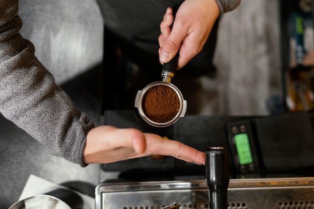 Vue de dessus du barista masculin tenant une tasse de machine à café professionnelle