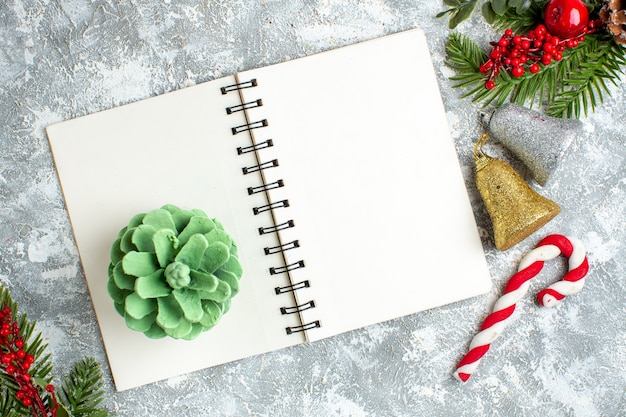 Vue de dessus du bloc-notes d'ornements d'arbres de Noël aux baies rouges de Noël sur un tableau blanc gris