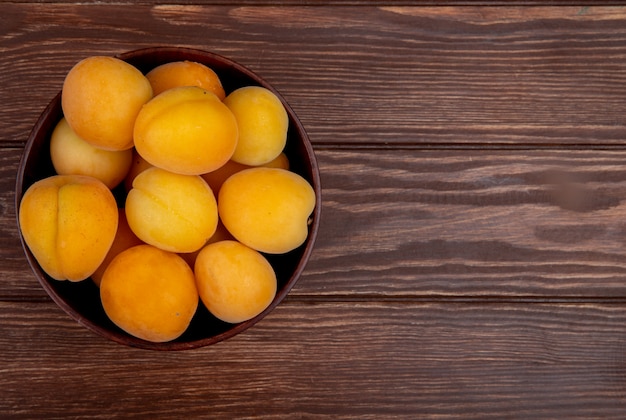 Vue de dessus du bol d'abricots sur fond en bois avec espace copie