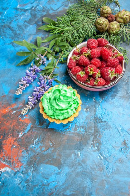 Vue de dessus du bol de framboises et petite tarte sur la surface bleue