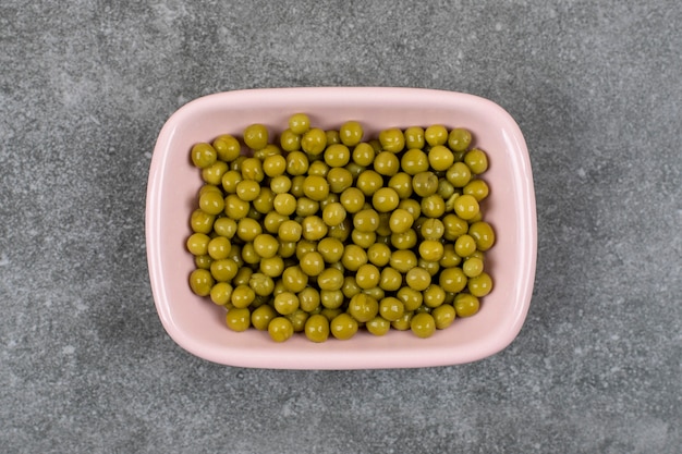 Vue de dessus du bol rose plein de pois verts en conserve