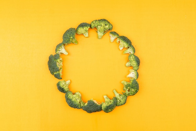Photo gratuite vue de dessus du brocoli frais disposé circulaire sur une surface jaune
