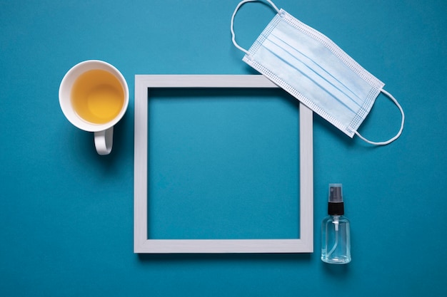 Photo gratuite vue de dessus du bureau avec cadre et masque médical à côté du thé