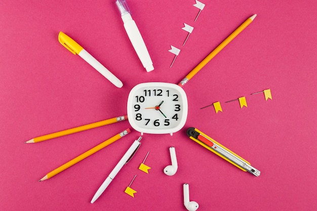 Vue de dessus du bureau avec horloge et une variété de stylos et crayons