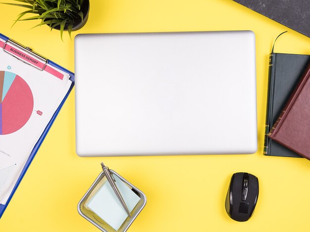 Vue de dessus du bureau jaune d'un homme d'affaires, livres, pot d'herbe, presse-papiers, notes, stylo