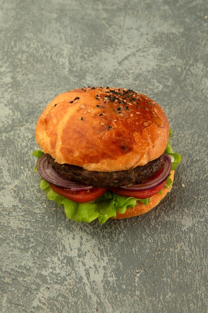 Vue de dessus du burger de boeuf avec laitue, tomate, oignon au fond gris uni